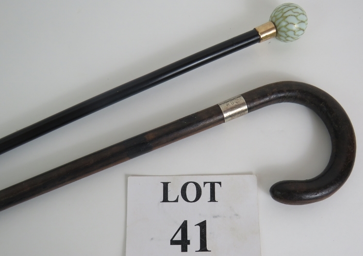 An early 20th Century ebony walking cane with enamelled porcelain knob and yellow metal collar