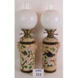 A pair of late 19th Century hand decorated porcelain based oil lamps with bird and blossom