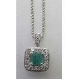 An 18ct white gold emerald and diamond pendant on an 18ct white gold adjustable chain. Emerald cut