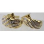 A pair of yellow metal diamond hoop earrings, each earring with forty baguette cut graduated