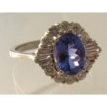 An 18ct white gold oval tanzanite & round brilliant cut and tapered baguette diamond cluster ring,