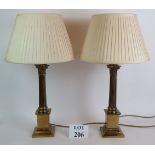 A pair of gilt brass Corinthian column table lamps with pleated fabric shades. Base height: 46cm.