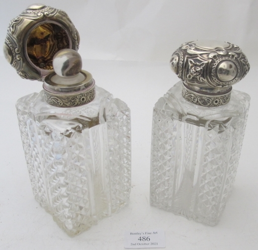 A pair of cut glass scent bottles with silver tops, London 1898, the silver tops embossed with