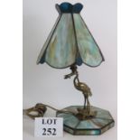 A decorative Chinese inspired stained glass lamp with support formed of a stork with a frog in its