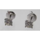 A pair of 18ct white gold four claw set round brilliant cut diamond solitaire stud earrings.