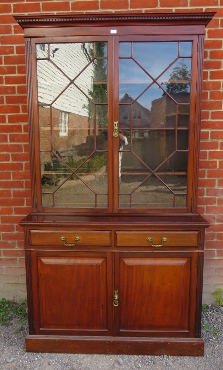 An Edwardian mahogany tall bookcase with dentil cornice over astral glazed doors opening onto