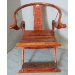 An early 20th century Chinese hardwood folding horseshoe chair, metal mounted and ornately carved