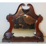 A late 19th/early 20th century shield shaped bevelled oval mantle mirror, the mahogany frame