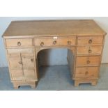 An antique pine kneehole desk, the base having an arrange of six drawers and a cupboard to one