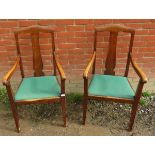 A pair of Edwardian oak framed high back armchairs, with lift out green seat pads, raised on