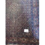 An early 20th Century Persian rug, red/blue with central hexagonal Medallion. Even wear/colour
