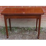An Edwardian mahogany turnover tea table with round corners, raised on tapering square supports,