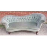 A Victorian sofa with ergonomically shaped backrests, upholstered in a green button velvet, raised