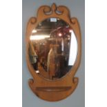A vintage pine oval mirror with scrolled cornice and shelf. 64cm high x 37cm wide x 10cm deep (