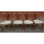 Set of four carved oak framed dining chairs upholstered in a cream material. Condition report: Old