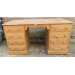 A striped pine kneehole desk containing eight short drawers each fitted with twin turned wooden knob