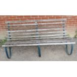 A nicely weathered vintage garden bench with oak slatted seat raised on green painted wrought iron