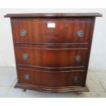 A small reproduction serpentine fronted bedside chest of three long drawers, raised on castors. 54cm