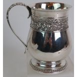 A George III silver pint mug of baluster form with embossed grape vine decoration, whip lash