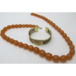 A graduated amber coloured necklace, approx 25" long, with a yellow metal clasp and a yellow metal