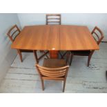 A mid century teak drop leaf dining table by McIntosh raised on cylindrical supports, together