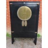 A 20th century Chinese black lacquered elm marriage cabinet, the double doors opening to reveal