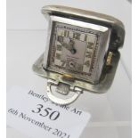 A small Art Deco silver travel clock, double shock proof made in Switzerland, with engine turned