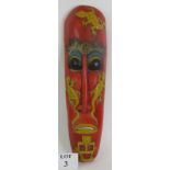 A hand carved Indonesian tribal mask with aged painted decoration and slit cut eye and mouth