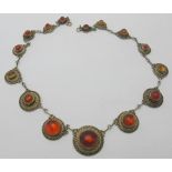 A fine amber mounted white metal necklace consisting of fifteen graduated amber discs joined