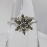 A white metal flower ring set with centre diamonds, approx .20pts and six petals each set with two