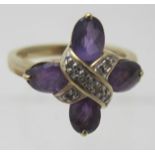 A 9ct yellow gold ring set with four oval shaped amethysts in a claw setting & a centre cross over