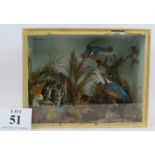 A taxidermy diorama featuring a pair of kingfishers feeding their five young in a riverbank setting.