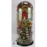 A large antique glass dome encasing an elaborate silk flower arrangement in a painted glass vase.