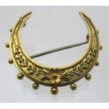 A 15ct gold crescent shaped brooch with flower decoration, approx weight 2.4 grams. Condition