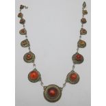 A fine amber mounted white metal necklace consisting of fifteen graduated amber discs joined