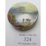 A silver & enamelled compact depicting a painting of highland cattle in the lakes of Scotland.