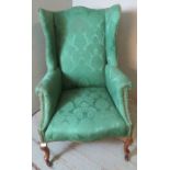 A 19th century wingback armchair upholstered in sage green damask fabric, raised on fruitwood