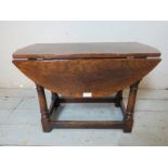 A reproduction oak diminutive drop leaf side table in an 18th century taste, raised on turned &