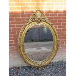 A large oval bevelled wall mirror in a very ornate gilt frame in the 18th century French taste