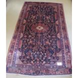 An antique Nahawand carpet. A central patterned motif set on a deep rich black ground softened by
