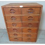 A vintage medium oak bank of twelve drawers each with recessed roundels featuring wooden bar