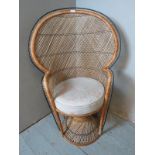 A vintage style wicker peacock chair featuring an intricately woven backrest, raised on a helix