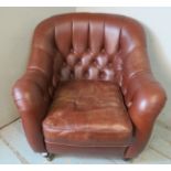 A button back club chair upholstered in distressed dark brown leather with brass studs, raised on