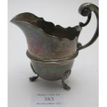 A silver cream jug on pad feet with double scroll handle & thumb piece, London 1892, approx weight