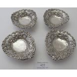 A set of four silver heart shaped bon bon dishes on ball feet, openwork design embossed with scrolls