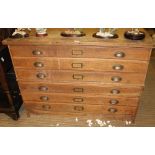 A MID 20TH CENTURY OAK FINISHED TWO-PART PLAN CHEST of six full width drawers, with brass cup