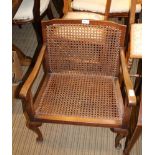 A LOW BACKED BERGERE SEATED ARMCHAIR