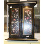 A BLACK FINISHED TWO DOOR KEY CABINET with panels of flora and fauna