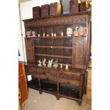 AN OAK TWO-PIECE DRESSER the plate stand back having carved frieze and twin carved panelled cupboard