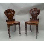 A PAIR OF WILLIAM IV PERIOD MAHOGANY HALL CHAIRS with fancy shaped and carved backs, and solid